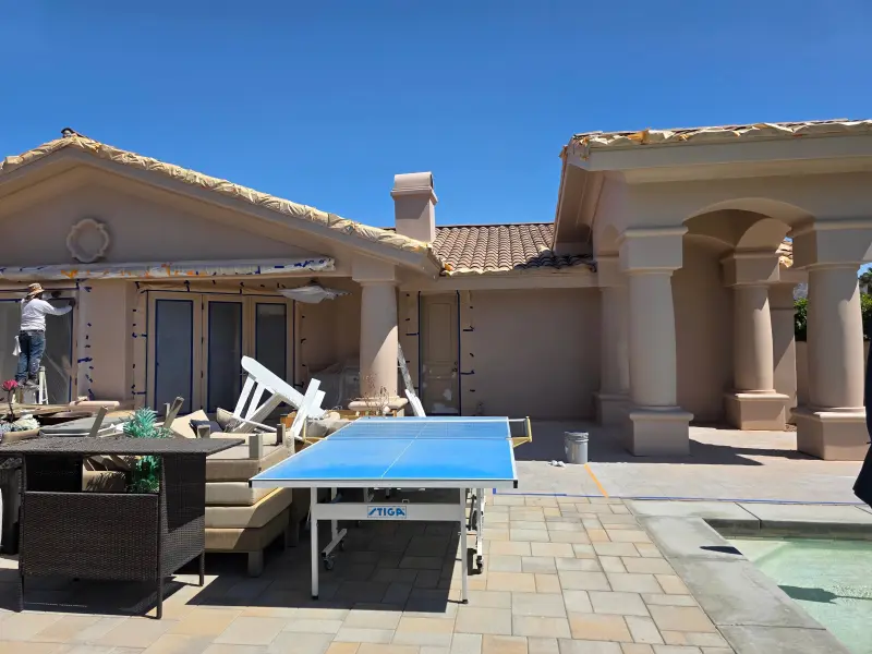 Elastomeric paint Indian Wells prep with painters masking windows on Mediterranean stucco home