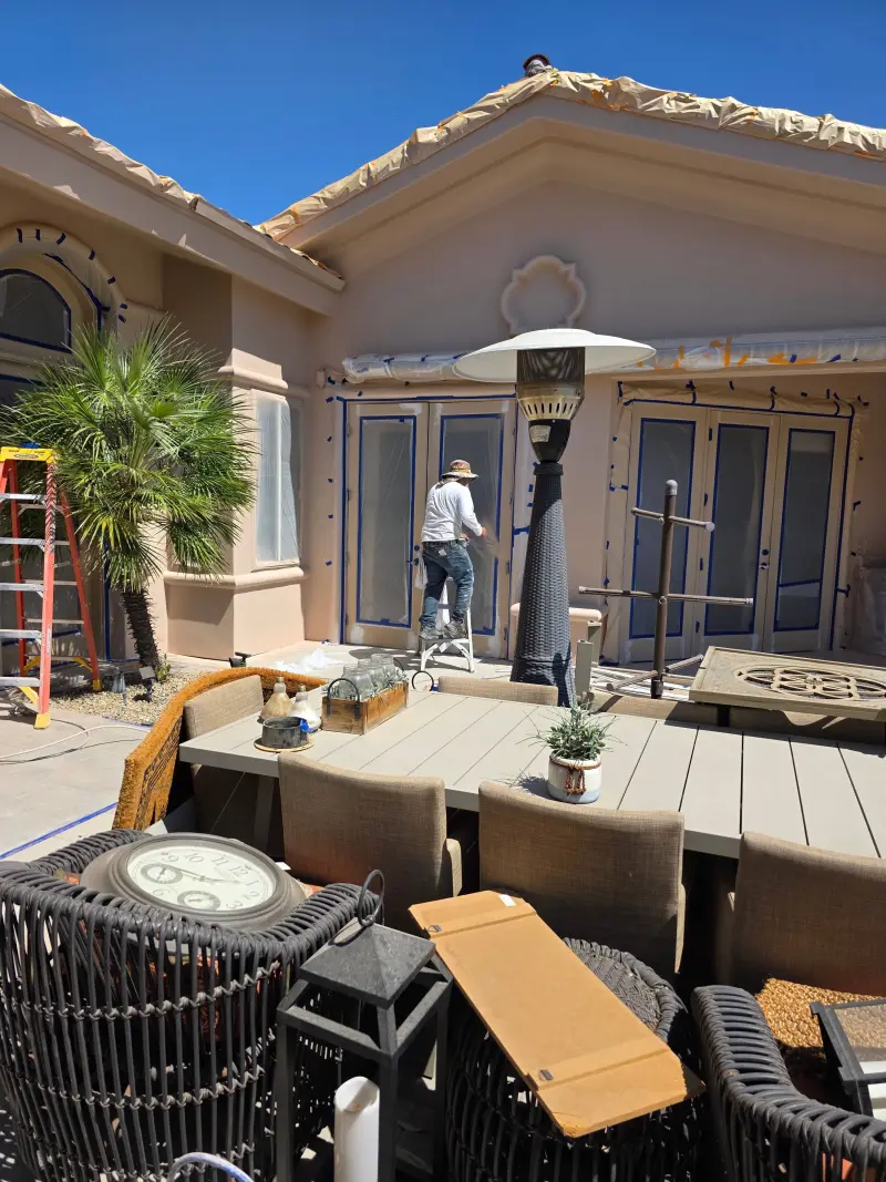 Painter masking windows and trim for stucco coating application in Indian Wells home