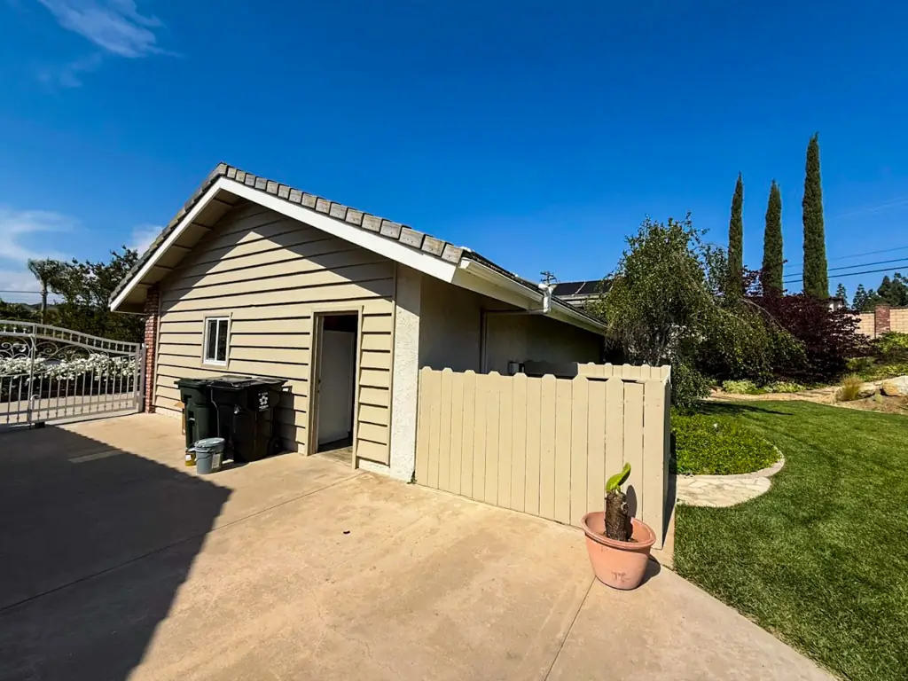 Stucco repair Yorba Linda in progress with restored siding and freshly painted fence