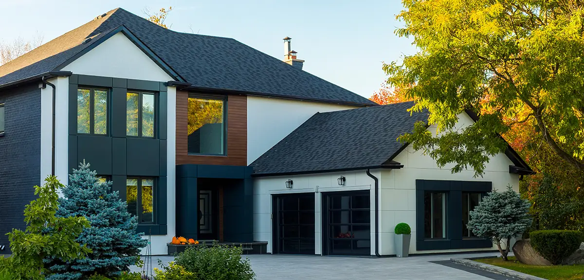 Modern house exterior with fresh paint, dark window frames, and a well-maintained lawn, showcasing a stylish and contemporary design.